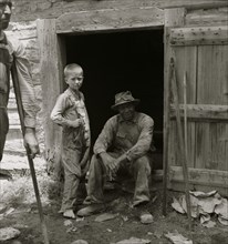 African American man sits in his cabin door while a young white child stands in front  1939