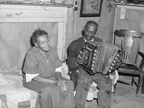 African American Mr. Dyson, aged FSA  borrower plays the accordion.  1940