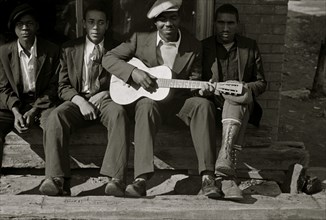 African American on bench while one plays the guitar 1935