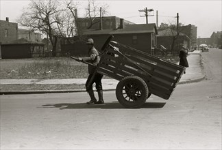 African American pulls a large cart through city streets 1938