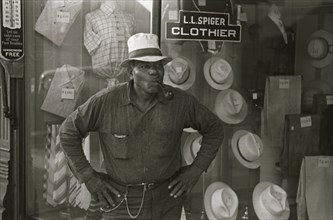 African American Resident of Plain City, Ohio smoking a pipe outside of a clothing store 1935