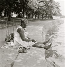African American woman, seated on ground, fishing, at the Tidal Basin, Washington, D.C. 1957