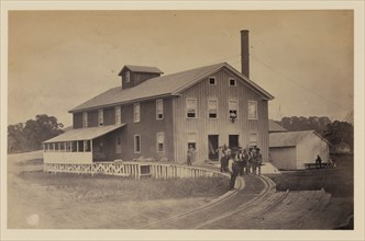 African American workers standing on railroad tracks in front of a storage facility, possibly at Giesboro cavalry depot 1863