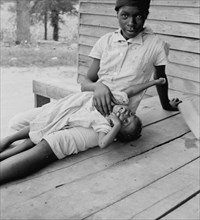African American young girl with a small child on a porch 1939