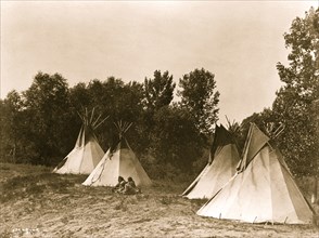 An Assiniboine camp containing four tepees with Indians seated on ground 1908