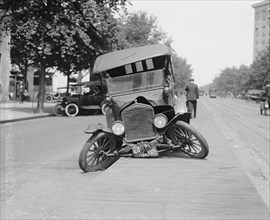 Automobile's Front axel breaks splaying tires outward causing vehicle to rest on its front bumper. 1922