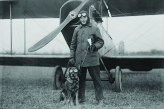 Aviator and His dog wear goggles in front of his Biplane