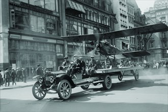 Biplane with spinning propeller is towed down Fifth Avenue New York for July 4th Parade