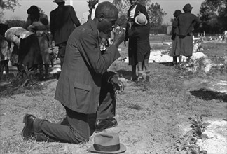 Black crossing himself and praying over grave of relative in cemetery, All Saints' Day, New Roads, Louisiana 1938