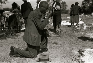 Black crossing himself and praying over grave of relative in cemetery, All Saints' Day, New Roads, Louisiana 1938