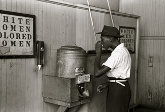 Black drinking at "Colored" water cooler in streetcar terminal, Oklahoma City, Oklahoma 1938