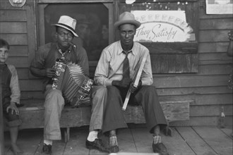 Black musicians playing accordion and washboard in front of store, near New Iberia, Louisiana 1938