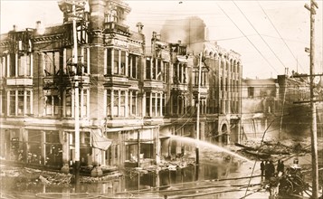 Block of burned buildings in San Francisco after the 1906 earthquake with fire truck spraying water on them 1906