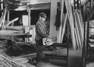 Boy probably about 13 years old, tying strips which he has taken away from the planer 1908