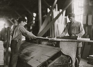 Boy working at double circular saws. N.Y. Dimension Supply Co. 1908