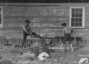 Two young boys from the Cotton Mill use a large crosscut saw 1908