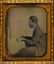 C.H. Hicks, in profile, seated at desk 1857