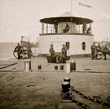 Charleston Harbor, S.C. Deck and officers of U.S.S. monitor Catskill; Lt. Comdr. Edward Barrett seated on the turret 1864
