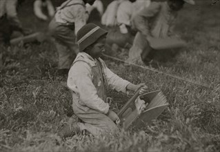 Charlie Fernande showing the scoop with which he works. Most of the scooping is done by adults. 1911