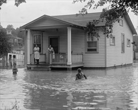 Children on porch of house surrounded by flood 1922