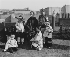 Chinese Mother with her children in Native Costume sit on rooftop 1901