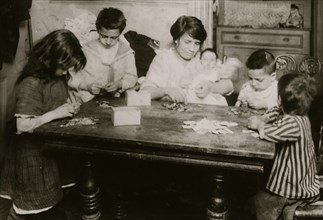 Italian family in their tenement apartment Working on patriotic flag pins.  1924
