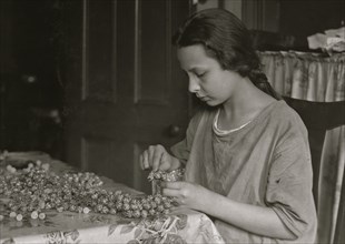 Cottage Industry shows young girl stringing material in piecework done at home. 1924