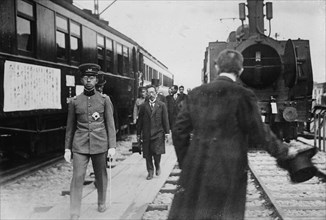 Crown Prince, in uniform walks beside a train at station