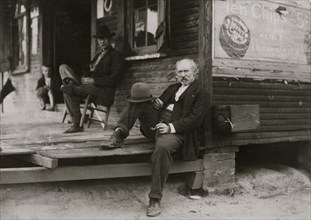 Dependent Widower sits on steps; the children work to support him 1911