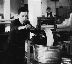 Edward McGurin, 14 years old. Wringing curtains at Boutwell, Fairclough & Gold, 274 Summer Street Extension. 1917