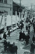 Election Day in Tokyo Japan shows a line of tables with signs in Kanji advertising political candidates