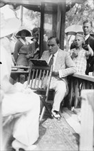 Enrico Caruso Leans back on chair holding a Board with Music