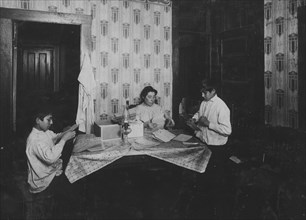 Family of David H. Goodman,. Mother and two children,  working on tags for Dennison factory. 1912