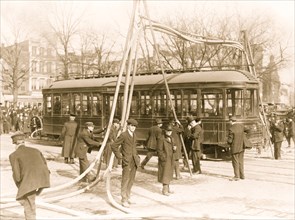 Firemen with hoses over streetcar 1914