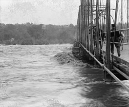Flood waters lap and rise against and threaten abridge across the river 1924
