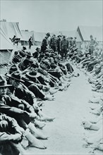Foot Inspection, soldiers sit on ground while doctors prepare to examine a full unit at once 1917