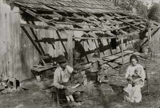 Frank Burditt and family. They rent this dilapidated shack and are trying to make a living off the meager land near by.  1921