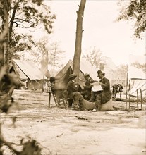 Gen. Ambrose E. Burnside (reading newspaper) with Mathew B. Brady (nearest tree) at Army of the Potomac headquarters 1863