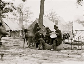 Gen. Ambrose E. Burnside (reading newspaper) with Mathew B. Brady (nearest tree) at Army of the Potomac headquarters 1864