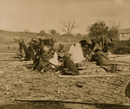 Group of Winnebago Indians seated on ground and logs 1864