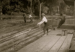 Hard work and dangerous. This "river-boy" Lyman Frugia. Poles the heavy logs into the incline that takes them up to the mill.  1914