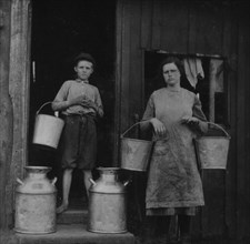 Holding pails and cans of milk 1916