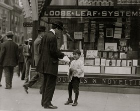 James Lequlla, Italian newsboy, 12 years of age. Selling newspapers in front of a stationery store. 1910