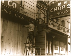 Japanese-American boarding up store front before evacuation, San Francisco 1942