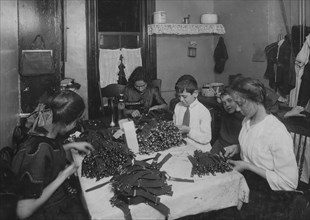 Jewish family working on garters in kitchen for tenement home 1912