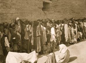 Line of Apache men, women, and children outside agency building on issue day, San Carlos, Arizona 1899