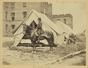 Major-General Joseph Hooker, full-length portrait, seated on horse, facing left, wearing military uniform, two tents and large building in the background 1863
