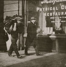 Man carrying bundle of garments. Bleeker St., N.Y.  1912
