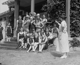 Matron points at Young Girls sitting on the steps of the beach house 1923