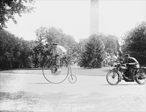 Motorcycle cop chases a Penny Farthing Velocipede down a DC Street with Washington Monument in background 1921